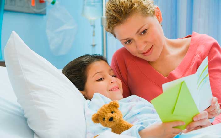 Child patient reading a get well card with her mom
