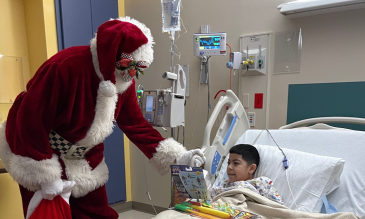 Santa delivering a present at STHS Children's