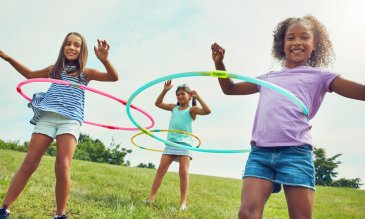young girls hula hooping in a park